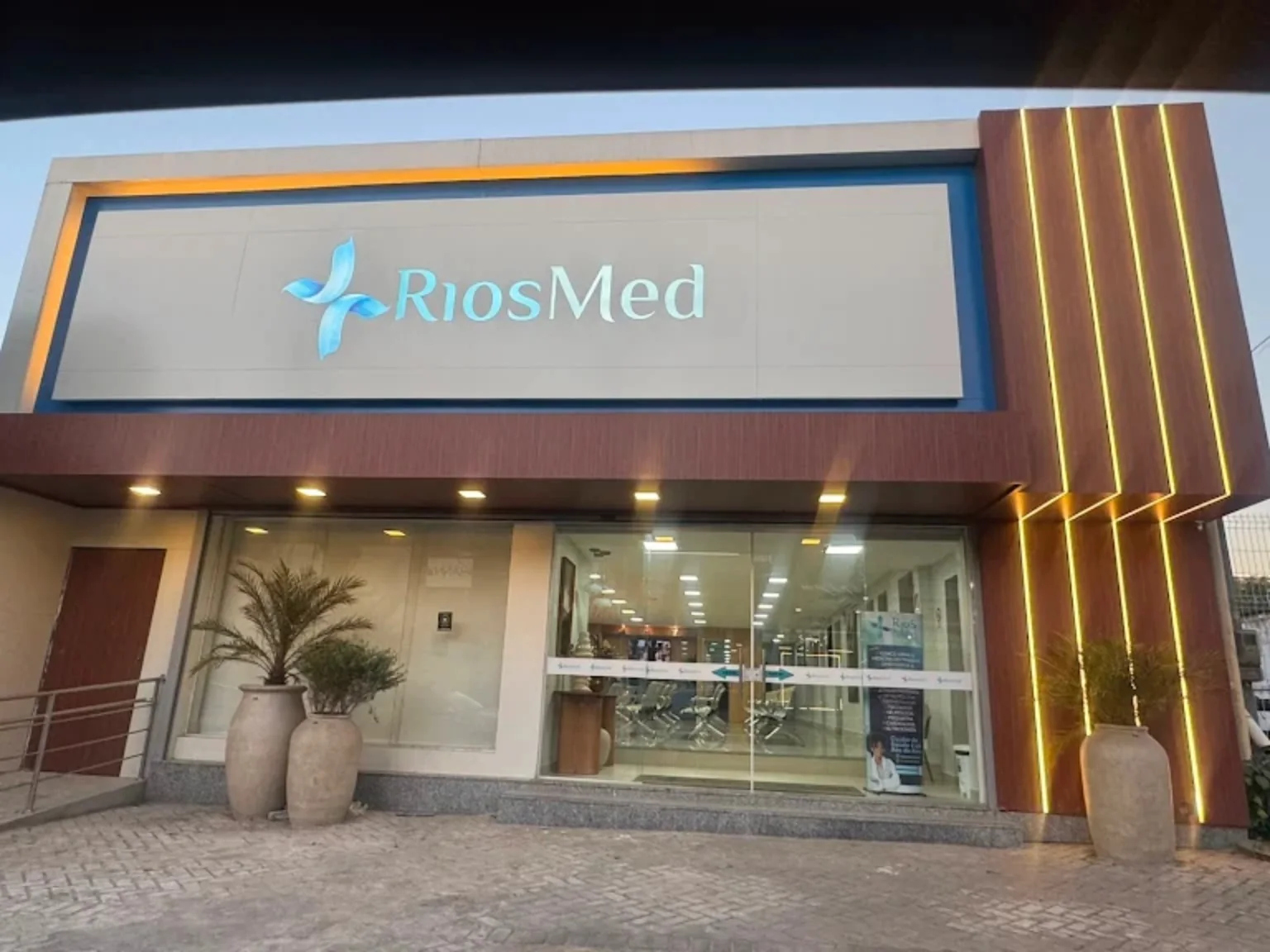 Fachada da RiosMed com letreiro, entrada de vidro e rampa de acesso.
