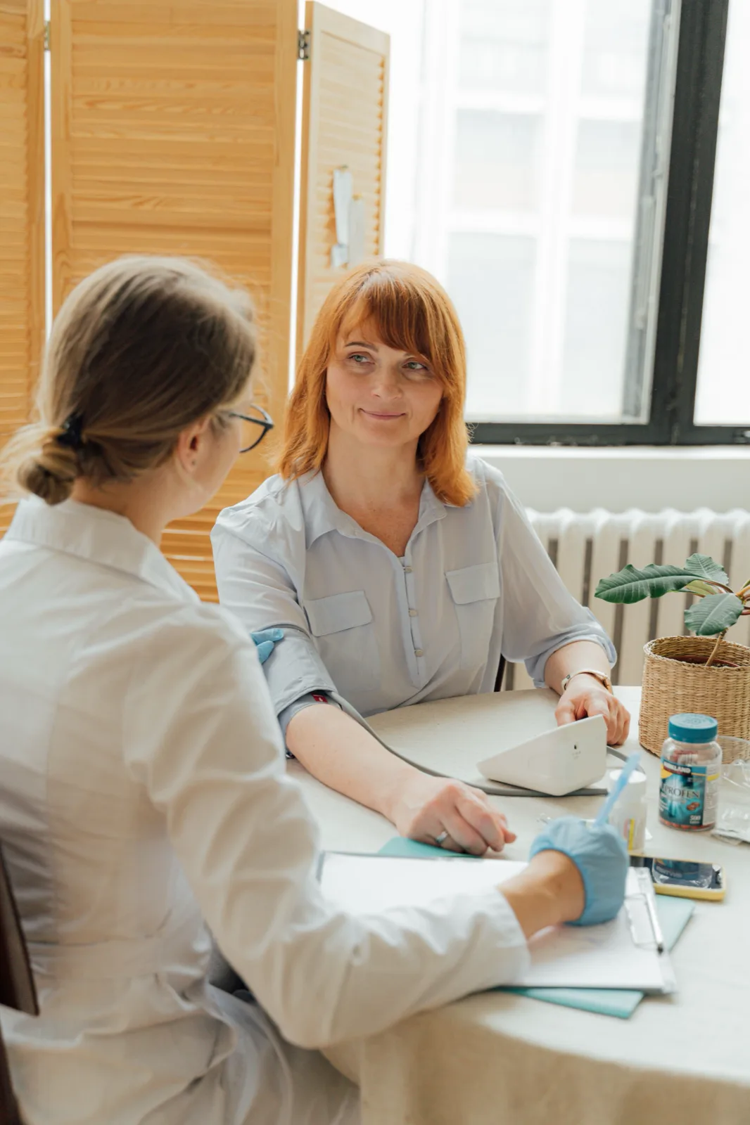 Mulher em conversa com profissional de saúde durante consulta, em fotografia ilustrativa.